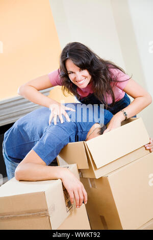Young playful couple unpacking boxes at new home Stock Photo