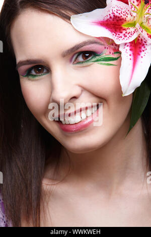 portrait of beautiful brunette with eye-zone body art posing with tiger lily Stock Photo