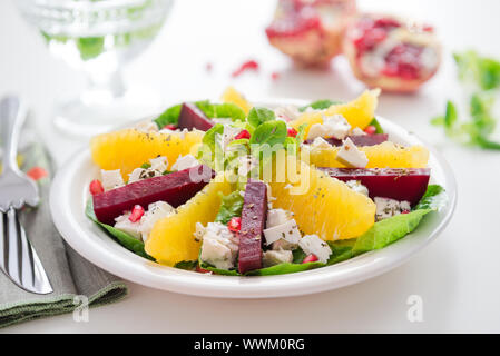 Salad with feta cheese, orange and beets, garnished with pomegranate seeds