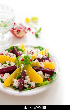 Salad with feta cheese, orange and beets, garnished with pomegranate seeds