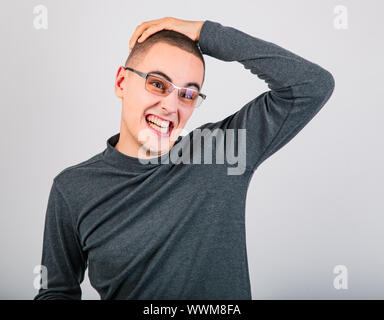 Crazy grimacing man in eye glasses holding the head on blue background. Closeup portrait Stock Photo