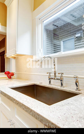 Large granite kitchen sink with window above it. Stock Photo