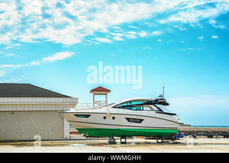 a snow white yacht stands on a pier on coasters on a Sunny day against a beautiful sky with clouds Stock Photo