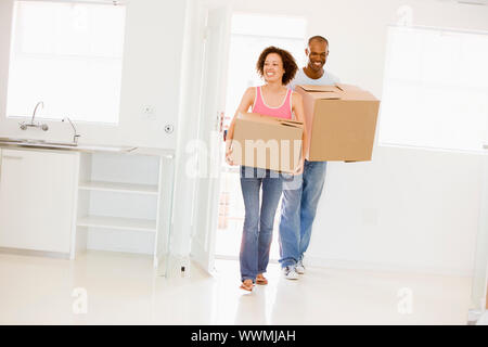Couple with boxes moving into new home smiling Stock Photo