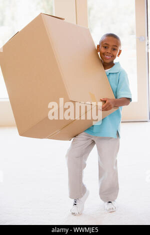 Young boy holding box in new home smiling Stock Photo