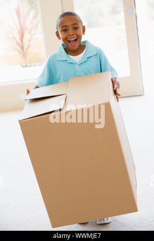 Young boy holding box in new home smiling Stock Photo