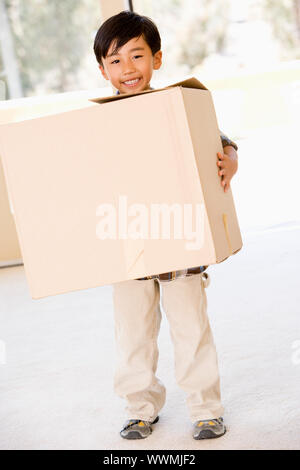 Young boy with box in new home smiling Stock Photo