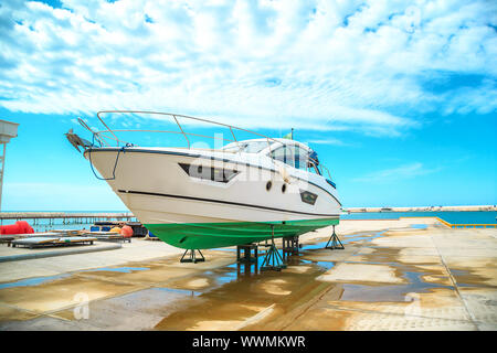 a snow white yacht stands on a pier on coasters on a Sunny day against a beautiful sky with clouds Stock Photo