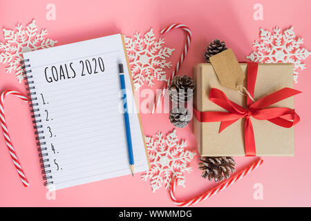 2020 New year concept. Goals 2020 list in notepad, gift box and christmas decoration on pink pastel color with copy space Stock Photo