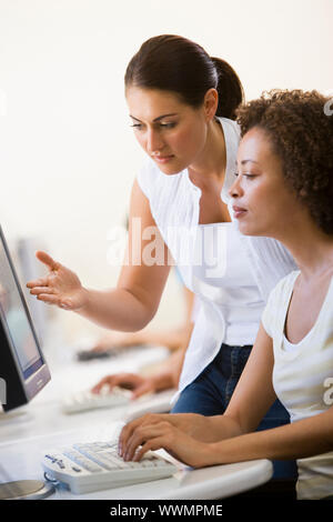 Two women in computer room where one is assisting the other Stock Photo