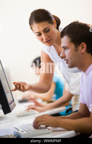 Woman assisting man in computer room Stock Photo