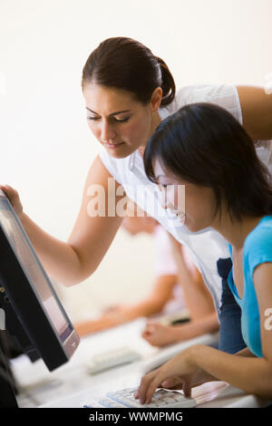 Two women in computer room where one is assisting the other Stock Photo