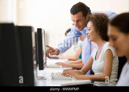 Man assisting woman in computer room Stock Photo