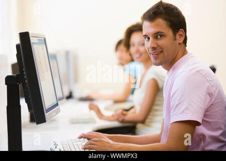 Three people sitting in computer room typing and smiling Stock Photo ...