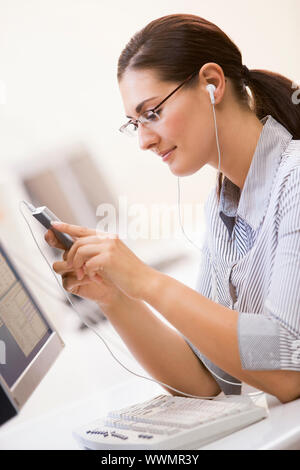 Woman in computer room listening to MP3 Player Stock Photo