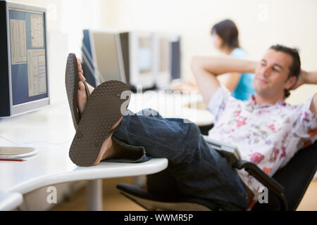 Man in computer room with feet up relaxing Stock Photo