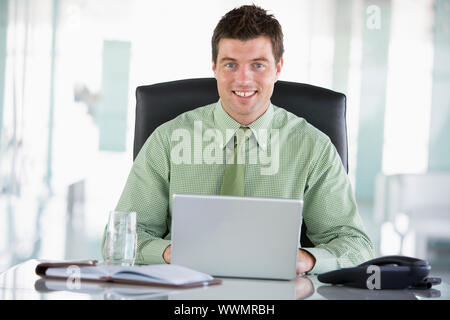 Businessman sitting in office with personal organizer using laptop Stock Photo