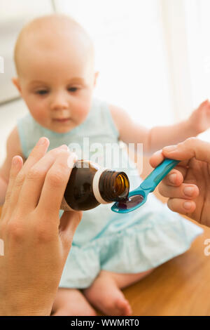Mother giving baby medicine indoors Stock Photo