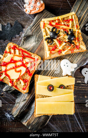Funny Halloween sandwiches for kids breakfast. Child Halloween party food concept. Old rustic wooden background copy space top view Stock Photo
