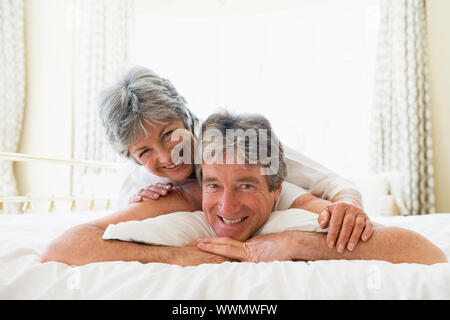 Couple lying on bed together smiling Couple lying on bed together smiling