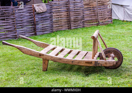 A rustic antique wooden wheelbarrow on grass. Stock Photo