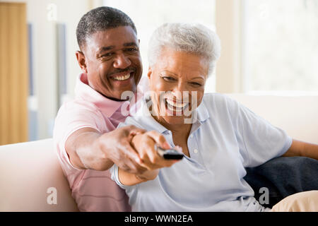 Couple in living room using remote control smiling Stock Photo