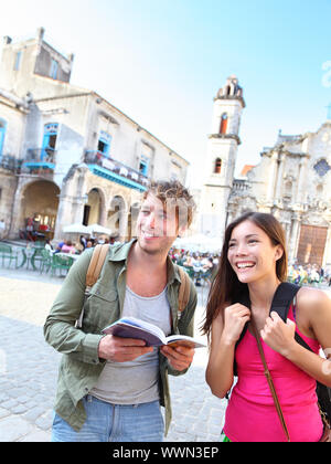 Tourists couple travel having fun smiling happy in Havana, Cuba . Young interracial happy couple on backpacking vacation standing holding reading tour Stock Photo