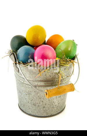 Sinc bucket with straw and colorful painted easter eggs Stock Photo