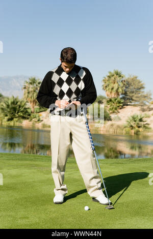 Golfer Marking Scorecard While Standing on Green Stock Photo