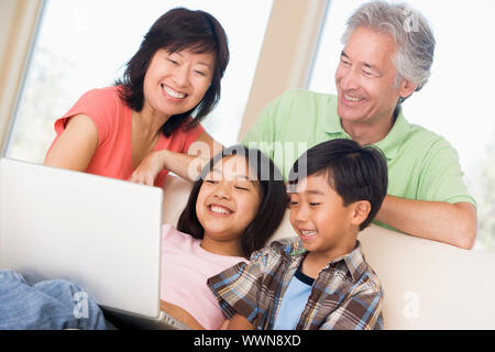 Couple with two young children in living room with laptop smilin Stock Photo