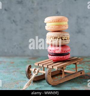 Stack of sweet french macarons cake on a decorative sled on blue background. Top view, copy space for text. Small French desert. Assorted Confectioner Stock Photo