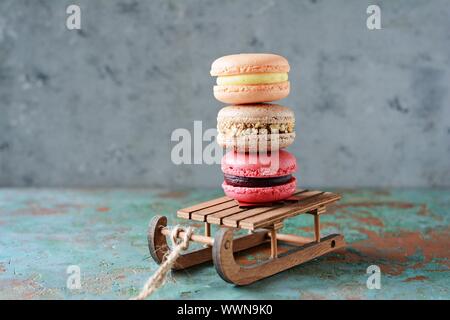 Stack of sweet french macarons cake on a decorative sled on blue background. Top view, copy space for text. Small French desert. Assorted Confectioner Stock Photo