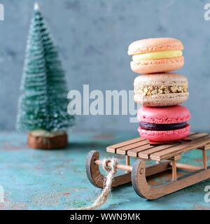 Stack of sweet french macarons cake on a decorative sled on blue background. Top view, copy space for text. Small French desert. Assorted Confectioner Stock Photo