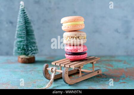 Stack of sweet french macarons cake on a decorative sled on blue background. Top view, copy space for text. Small French desert. Assorted Confectioner Stock Photo