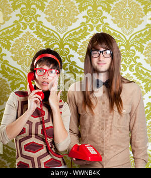 funny nerd humor couple talking retro vintage red telephone on wallpaper Stock Photo