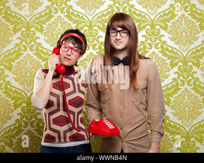 funny nerd humor couple talking retro vintage red telephone on wallpaper Stock Photo