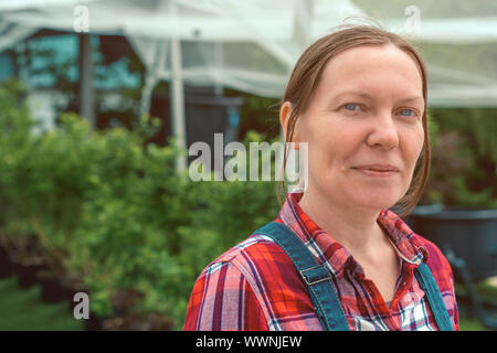 Female farmer in apple orchard with bird netting, portrait of confident woman farm worker Stock Photo