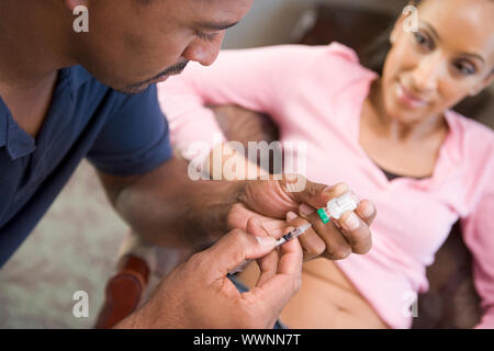 Man helping woman inject drugs to achieve pregnancy at home Stock Photo