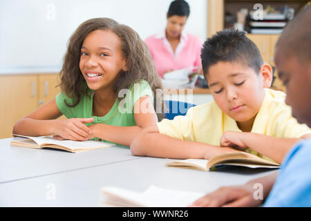 Pupils reading whilst sitting at desks Stock Photo