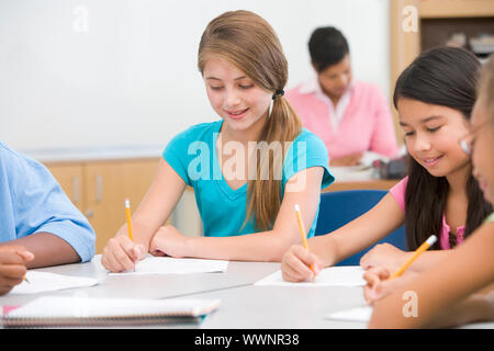 Elementary school pupils in classroom working at desk Stock Photo