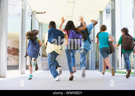 Rear view of elementary school pupils running outside Stock Photo