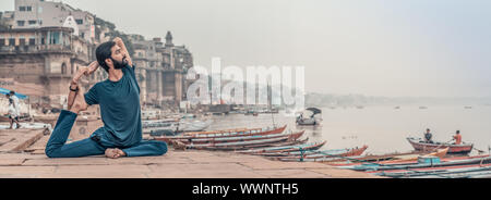 A yoga teacher sitting in a asana position next to the Ganges river in India. Stock Photo