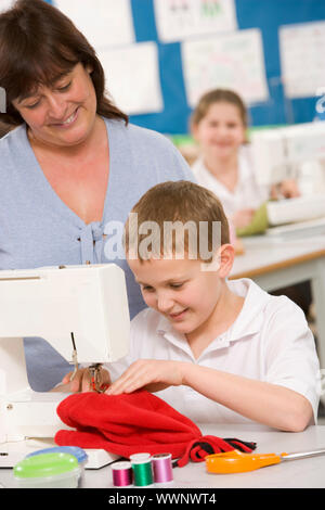 Male student using sewing machine with teacher Stock Photo