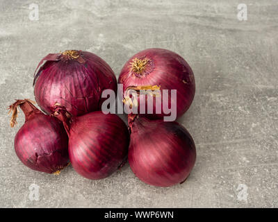 Close-up of five red onions on gray background. Selective focus. Stock Photo