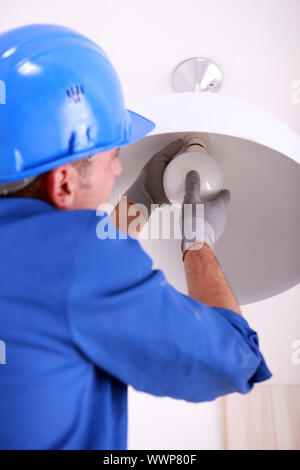 Electrician fitting a ceiling light Stock Photo