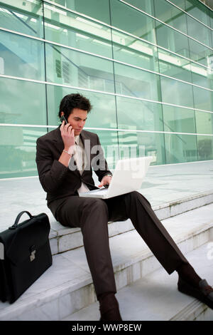 Businessman sat on steps working Stock Photo