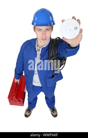 Electrician holding up smoke alarm Stock Photo