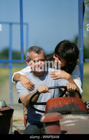 Couple riding tractor Stock Photo