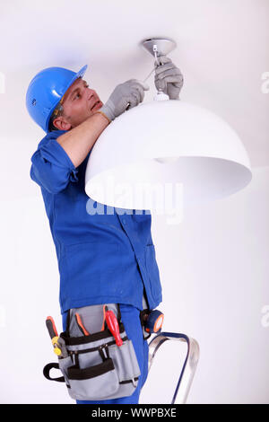 An Electrician installing a ceiling light fitting Stock Photo - Alamy