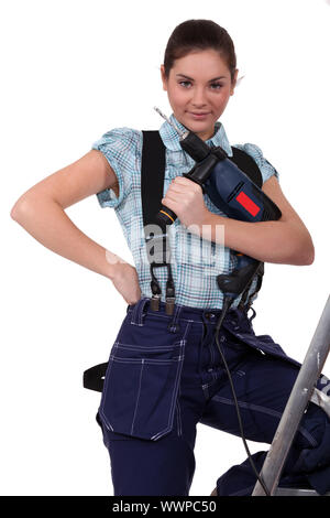 cute teenage apprentice holding electric drill with leg resting on ladder Stock Photo